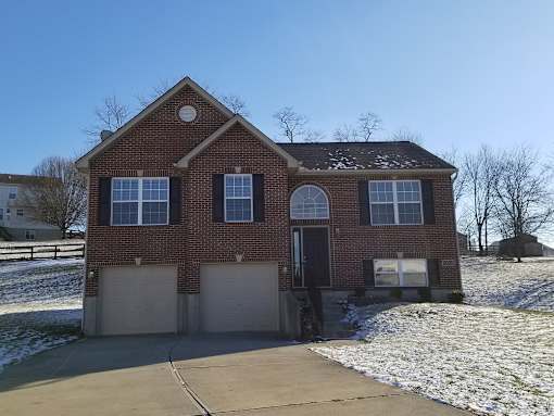 A red brick house with a black door and two garage doors.