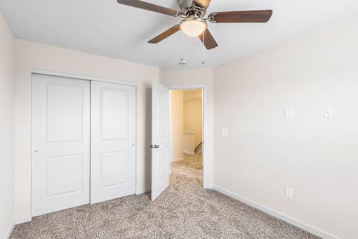 A room with a ceiling fan and carpeted floor.