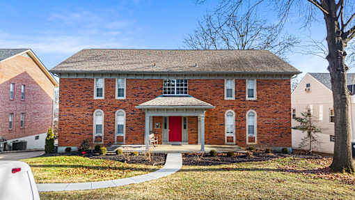 A red brick house with a red door and a grey roof.