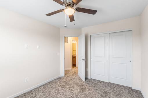 A room with a ceiling fan and carpeted floor.
