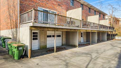 A parking lot in front of a red brick building with a balcony.