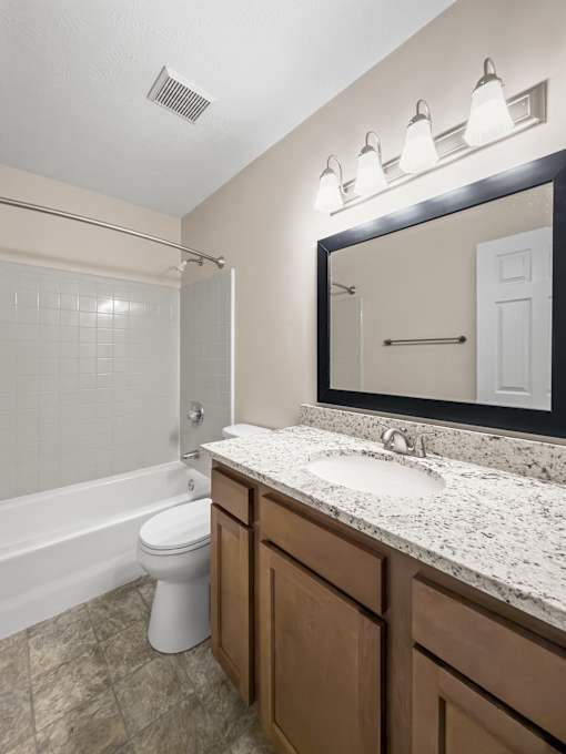 A bathroom with a toilet, sink, and mirror.