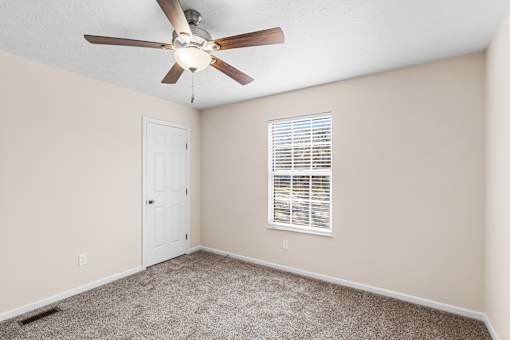 A room with a ceiling fan and a window with blinds.