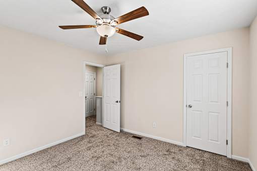 A room with a ceiling fan and carpeted floor.