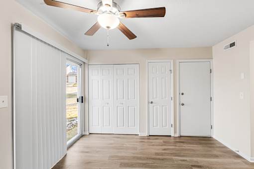 A room with a ceiling fan and three doors.