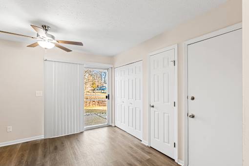 A room with a ceiling fan and white doors.