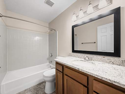A bathroom with a white toilet and a white bathtub.