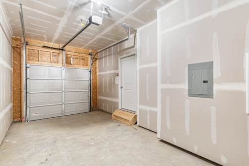 A room under construction with a garage door and a door on the right.