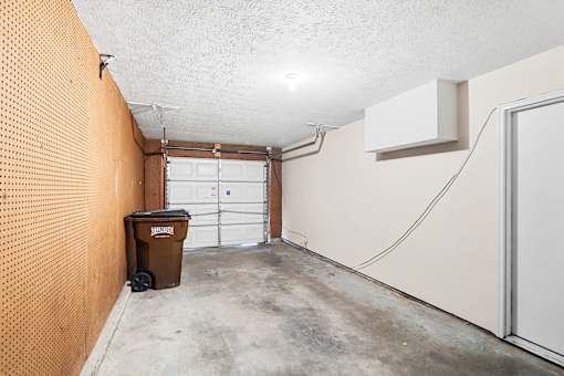 A brown trash can sits in a concrete garage.