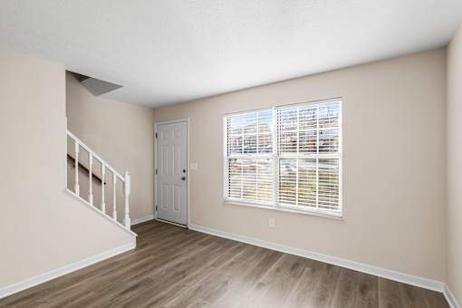 A room with a staircase and a window with blinds.