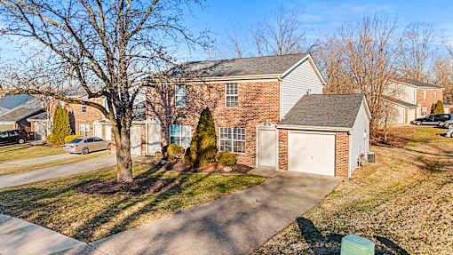 A house with a driveway and a tree in front.