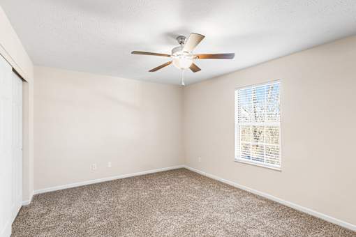 A room with a ceiling fan and a window with blinds.