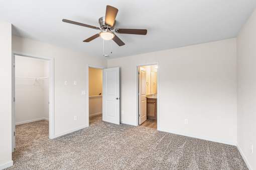 A room with a ceiling fan and carpeted floor.