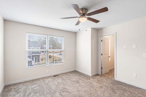 A room with a ceiling fan and a window overlooking a cityscape.