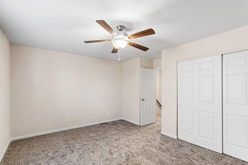 A room with a ceiling fan and carpeted floor.