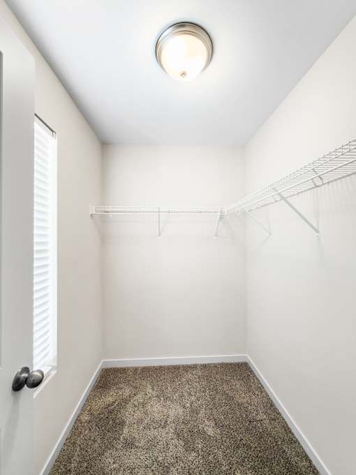 A small, empty room with a carpeted floor and a ceiling light.