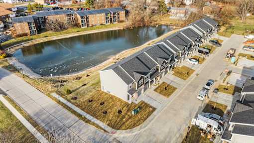 A row of houses with a pond in front of them.