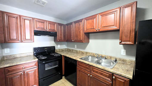 A kitchen with black appliances and wooden cabinets at Maplehurst Apartments, Tennessee 37902