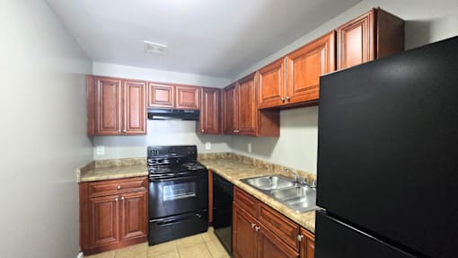 A kitchen with black appliances and wooden cabinets.