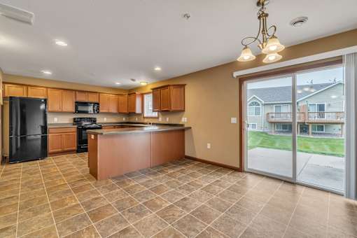A kitchen with brown cabinets and a black refrigerator.