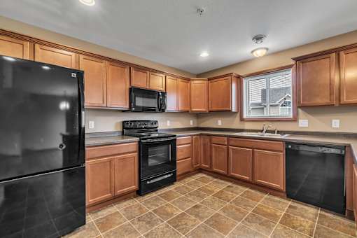 A kitchen with black appliances and brown cabinets.