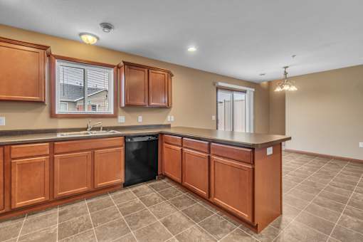 A kitchen with brown cabinets and a black dishwasher.