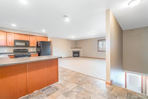 A kitchen with wooden cabinets and a black refrigerator.