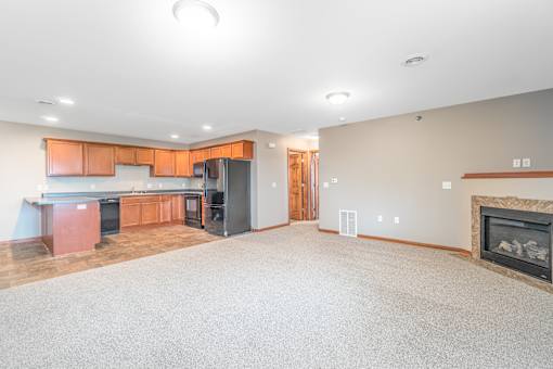 A spacious living room with a fireplace and a kitchen area in the background.