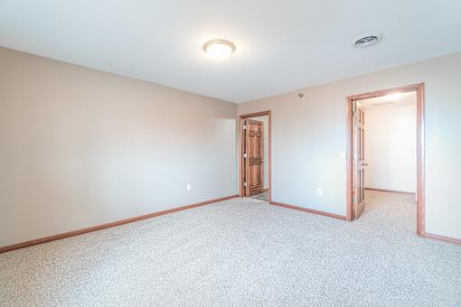 A room with a carpeted floor and two doors.