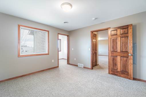 A room with a wooden door and a window with blinds.