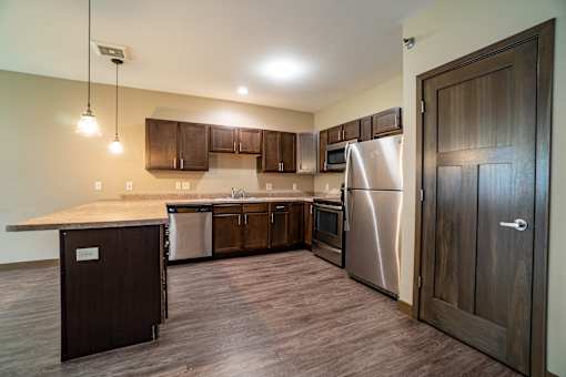 A kitchen with a stainless steel refrigerator and wooden cabinets.
