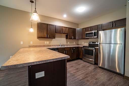 A kitchen with a stainless steel refrigerator and wooden cabinets.