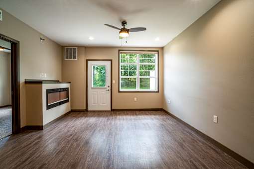 A room with a ceiling fan and a window with a view of trees.