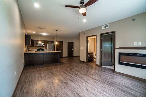 A modern kitchen with dark wood floors and a ceiling fan.