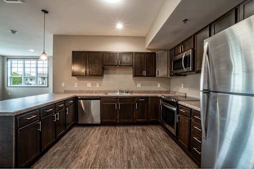 A modern kitchen with dark wood cabinets and stainless steel appliances.
