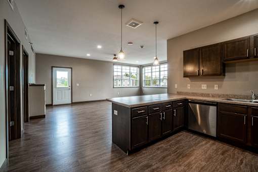 A kitchen with dark wood cabinets and a stainless steel dishwasher.