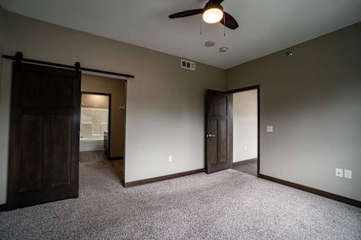 A room with a ceiling fan and carpeted floor.