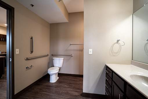 A bathroom with a toilet, sink, and mirror.