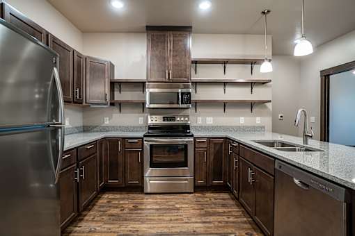 A modern kitchen with wooden floors and stainless steel appliances.