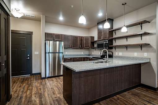 A kitchen with a stainless steel refrigerator and wooden floors.