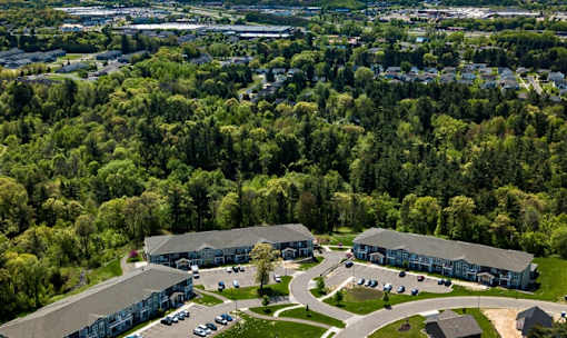 A large building complex surrounded by trees and a parking lot.