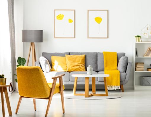 A living room with a grey couch, yellow chair, and two yellow pillows.