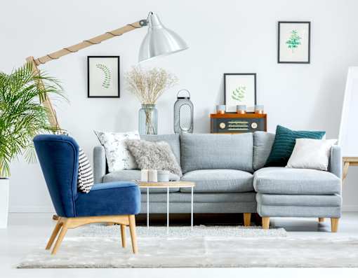 A living room with a grey couch, a blue chair, and a white floor lamp.