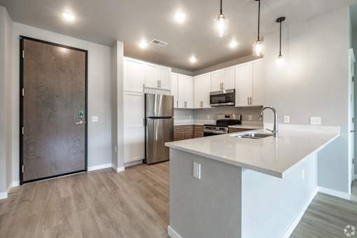 A modern kitchen with a wooden door and stainless steel appliances.