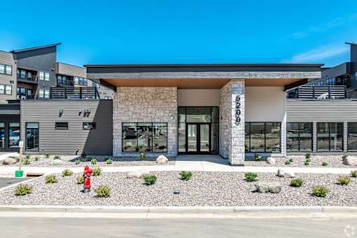 A modern building with a stone facade and a red fire hydrant in front.