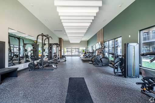 A spacious gym with a variety of equipment and a long mirrored wall.