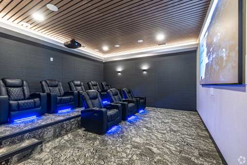 A home theater with black leather chairs and a wooden ceiling.