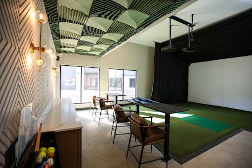 A room with a green mat on the floor and a black screen on the wall.