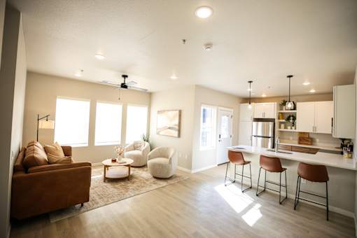 A modern kitchen with a brown couch and white chairs.