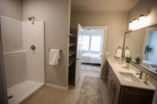 A bathroom with a white tiled shower and a white sink.